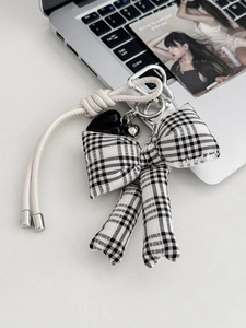 Detail van geruite strik sleutelhanger met zwarte hartvormige hanger en zilveren hartdecor
