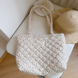 Detailed close-up of quilted floral tote bag with pink flowers on white fabric