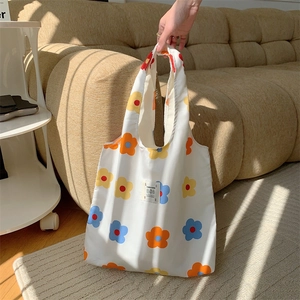 Dettaglio della borsa tote in tela floreale con stampe di fiori arancioni e blu e marchio