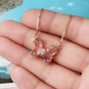 Detailed macro of pink crystal butterfly pendant with small diamonds on rose gold chain