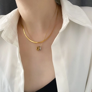 Elegant gold double layer snake chain necklace with silver rings worn by a female model