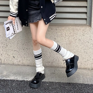 Y2K style white knitted leg warmers with black platform shoes on an outdoor street