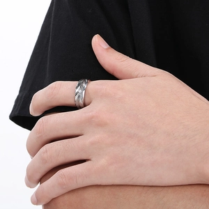 Macro detail of men's stainless steel feather ring with central crystal and textured finish