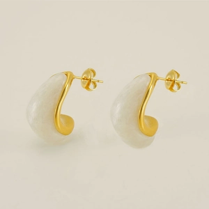 Detail of vintage gold plated stainless steel teardrop earrings with white resin inlay