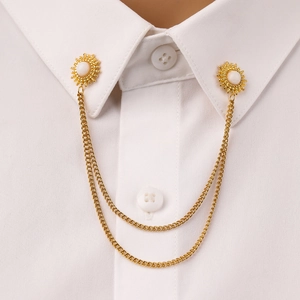 Close-up of golden sun-shaped collar pins with white pearls and double chains on a shirt