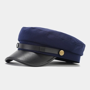 Detail of navy sailor cap featuring textured blue fabric and black leather brim accent