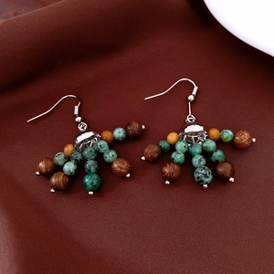 Détail macro de boucles d'oreilles vintage avec perles en bois brun et pierre verte