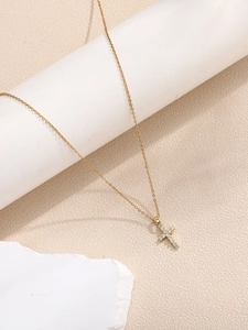 Detail of gold cross pendant with micro-paved white crystals on gold chain necklace