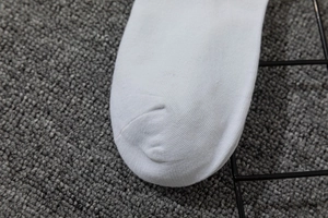 Detailed macro shot of white knitted cotton sock toe with seamless reinforced stitching
