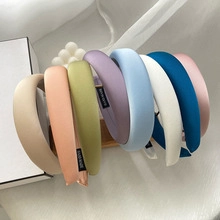 Close-up of handmade satin scrunchies in various colors displayed on a wooden stand