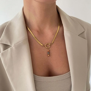 Close-up of a gold snake chain necklace with three colored beads on a female model