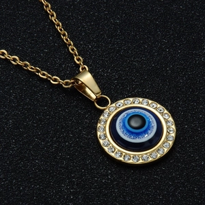 Vue macro d'un collier pendentif Œil Maléfique plaqué or 18 carats avec serti de zircons