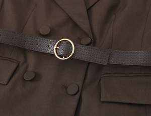 Detail of coffee brown textured belt with gold round buckle on matching fabric trousers