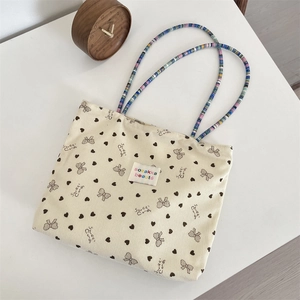 Dettaglio della borsa tote in velluto beige con stampa coral e manici decorati