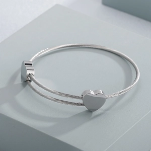 Detailed macro view of silver steel rope bracelet with polished heart charms
