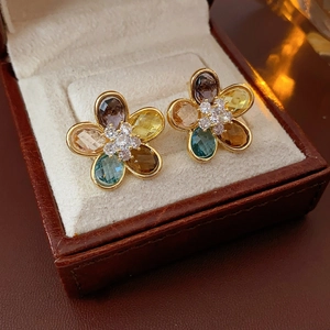 Detailed macro view of colorful flower zircon earrings on a beige velvet jewelry case