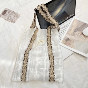 Détail de broderie florale sur sac en toile avec bandoulières à franges marron