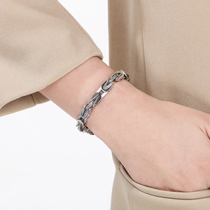 Close-up of a silver stainless steel braided chain bracelet worn on a model's wrist