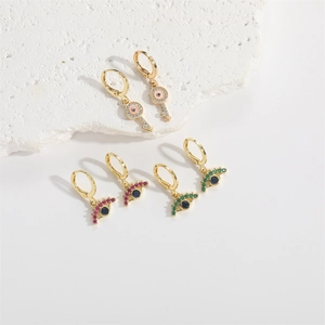 Golden evil eye and key drop earrings set with colorful gemstones on a stone base