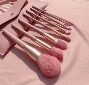 Detail of pink makeup brush set with gradient bristles and rose gold ferrule in storage bag