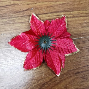 Flat lay of red Christmas flower with gold glitter edges on wooden background