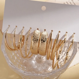 Ten-pair set of minimalist gold hoop earrings in heart and round shapes on display