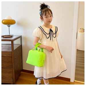 Detail of neon green thermal lunch bag carried by a girl in navy style dress
