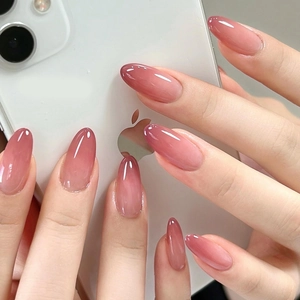 Faux ongles ovales dégradés rose avec finition brillante présentés sur les mains