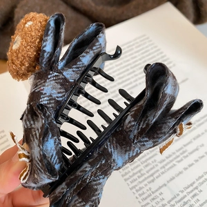 Detail of a plush bear bow hair claw clip with dark blue plaid and brown textures