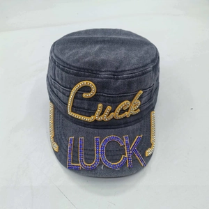 Detail of washed dark grey military cap featuring blue rhinestone LUCK text on the brim
