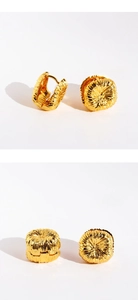 Macro detail of golden flower cluster earring showing intricate pleated texture and shiny finish