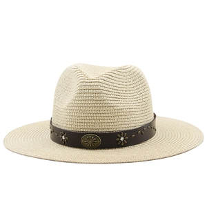 Detail of woven straw texture with brown leather band and metallic floral ornaments