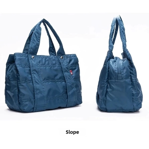 Detailed side view of a blue quilted nylon tote bag with zipper closure and soft texture