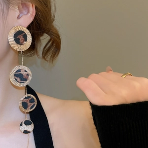 Detail of leopard print geometric round leather tassel earrings on female model