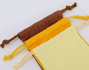 Detail showing stacked brown, orange, and beige cotton drawstring storage pouches