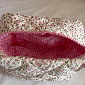 Detail view of floral quilted makeup bag with pink checkered lining and zipper