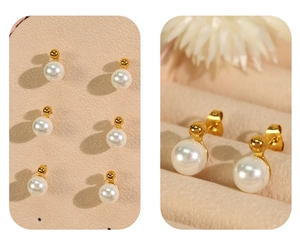 Detail showing white pearl earrings with golden ball backings and butterfly closures