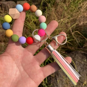 Detail of colorful silicone beaded bracelet keychain with leather tassel in hand