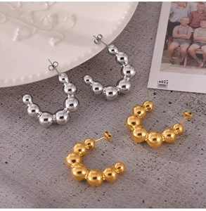 Detail view of C-shaped titanium steel earrings with gradient metal beads in gold and silver