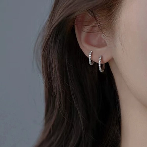 Élégantes créoles en argent 925 avec zircons portées sur l'oreille du mannequin
