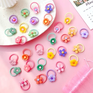 Colorful flower-shaped baby hair ties in a white bowl on pink background for girls