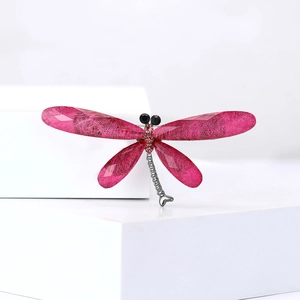 Macro detail of dragonfly brooch with rose red crystals and textured wings on silver alloy
