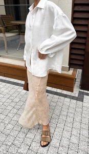Detail van wit oversized linnen overhemd en bloemenrok met zomerse sandalen