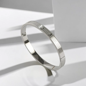 Detailed close-up of musical note engraving on a silver oval stainless steel bangle