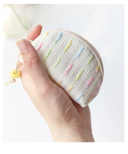 Detailed view of mini beige embroidered coin purse size held in hand for scale
