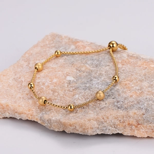 Adjustable gold bead bracelet with frosted and polished beads on stone background