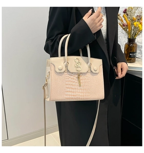 Détail du cabas en simili crocodile beige et rose avec logo doré et pompon élégant