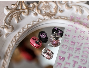 Macro shot of 3D matte bow nail stickers with heart and lace embossed decorative patterns