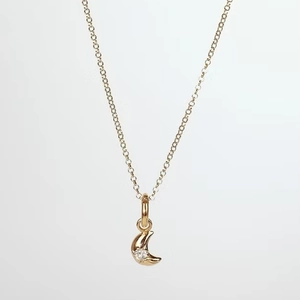 Detail of a gold crescent moon pendant with a sparkling zircon on a thin chain