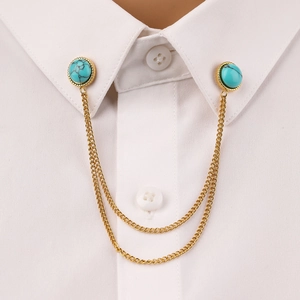 Close-up of golden collar pin with turquoise stones on a white shirt collar